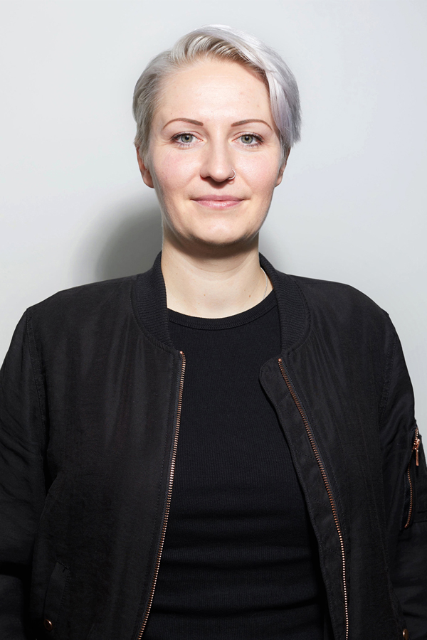 Employee photo of Anna-Katharina Meßmer. She wears a black jacket and stands in front of a white wall.