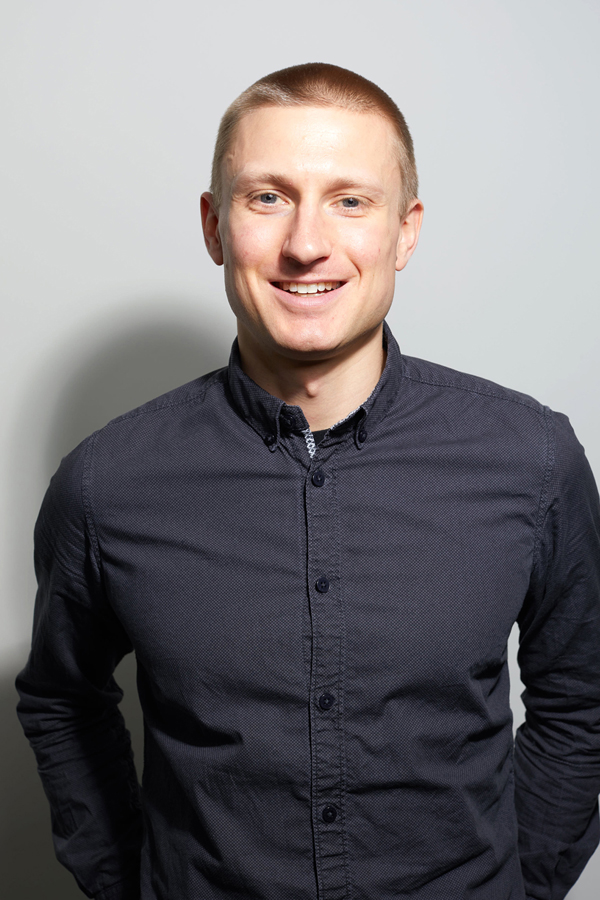 Employee photo of Julian Jaursch. He wears a dark blue shirt and stands in front of a white wall.