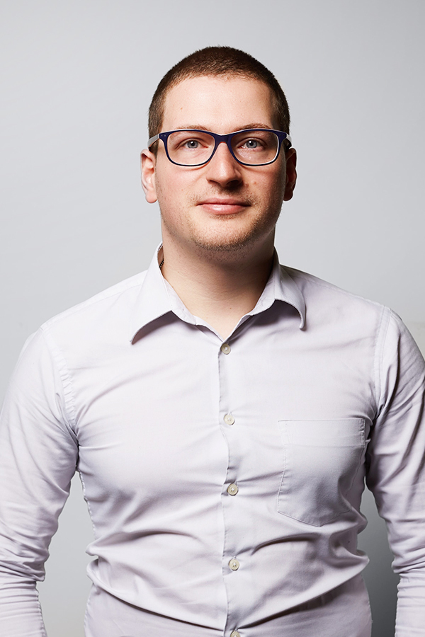 Employee photo of Sven Herpig. He is wearing a white shirt and standing in front of a white wall.