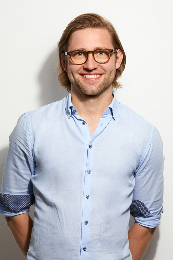 Employee photo of Laurenz Hemmen. He wears a light blue shirt and stands in front of a white wall.