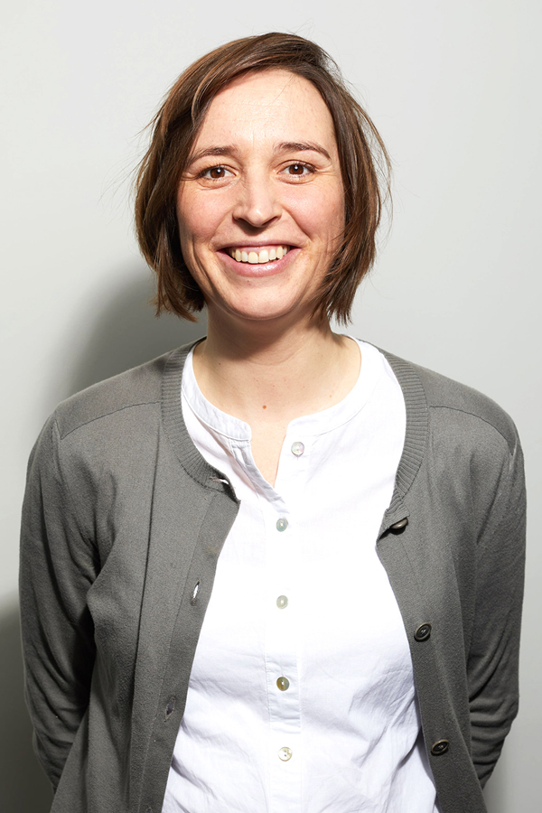 Employee photo of Anna Wohlfarth. She is wearing a gray cardigan and standing in front of a white wall.